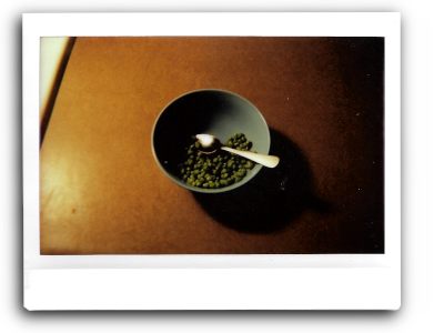 an instant picture of a blue bowl of green peas on a brown counter