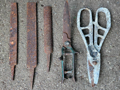 a row of rusty tools on concrete, files and shears