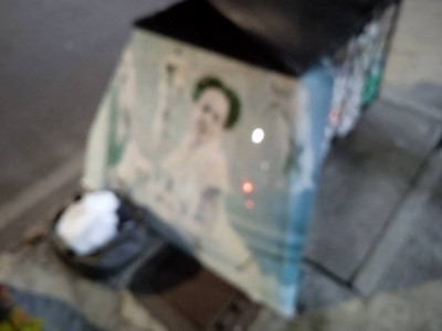 an out of focus picture of a poster of a woman sitting out on the curb by the trash